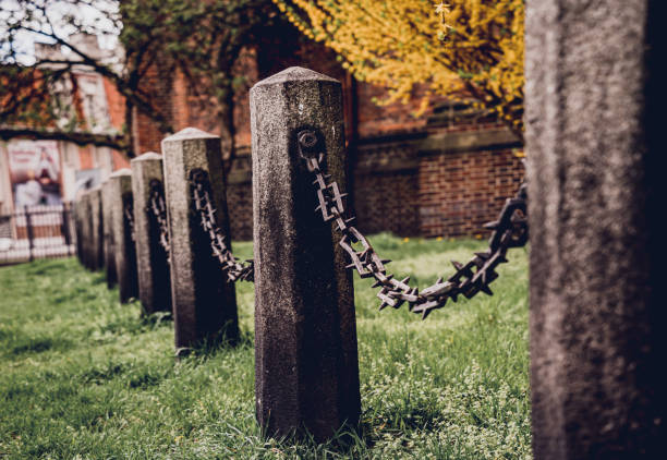 istock Old stone posts with chains on a background of green grass 1635289711