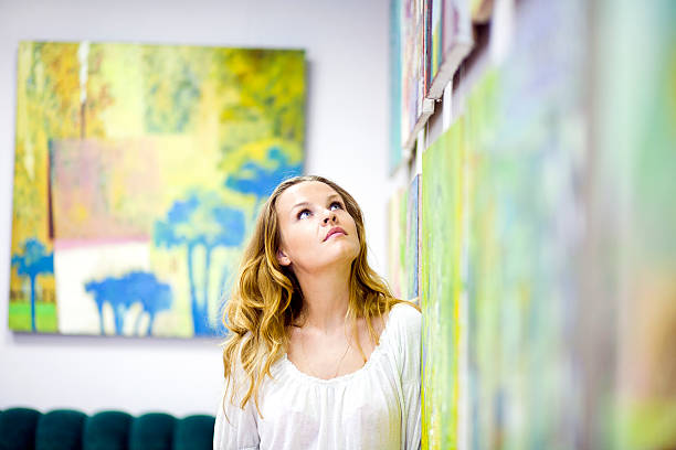 woman gazing at artwork on the wall - konstmuseum bildbanksfoton och bilder