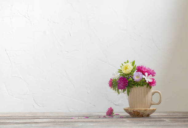istock beautiful flowers in cup on wooden table on background white wall 1635339290