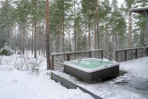 A modern outdoor hot tub embedded into the terrace on a cold winter's day. Warm outdoor hot tub helps to alleviate stress and rejuvenate the senses, providing a soothing escape from the demands of daily life.