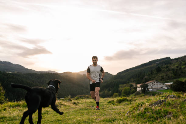 istock Young man running in the mountains with dog 1635340292