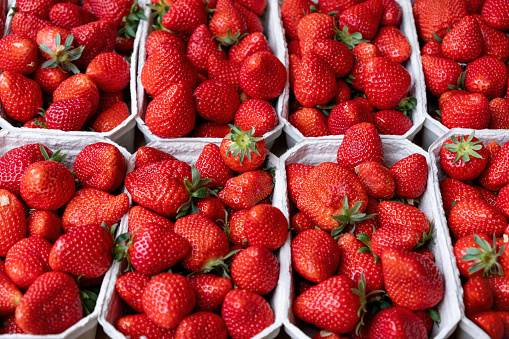 Strawberry in plastic container background, texture. Close up view of sweet healthy red fruit in white package. Proper food for vegetarian, diet.