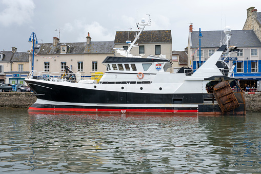 Port-en-Bessin-Huppain, France - 07 24 2023: A blue fishing boat entering the harbor