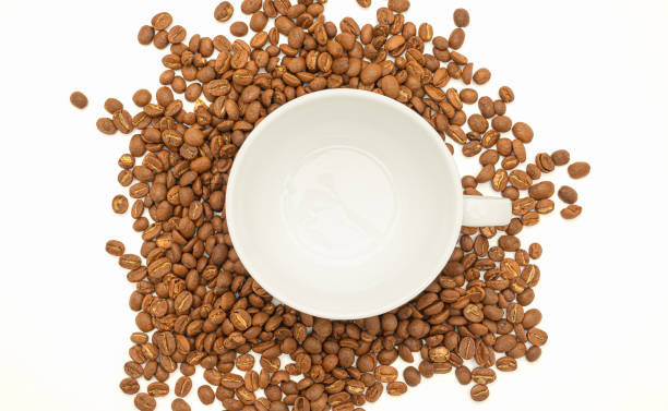 istock Top view of fresh aromatic roasted coffee beans and an empty white coffee cup on a white background 1635388129