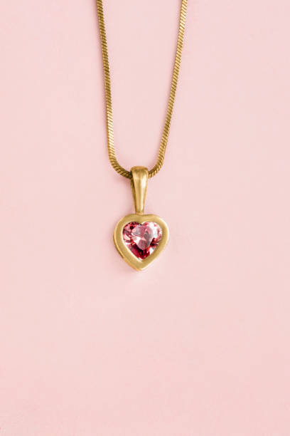 Heart necklace on pink Golden heart red crystal pendant on pastel pink background hanging stone stock pictures, royalty-free photos & images