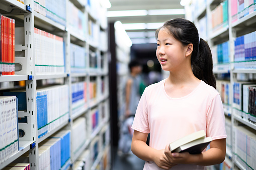 Asian junior high school student borrowing books in public library