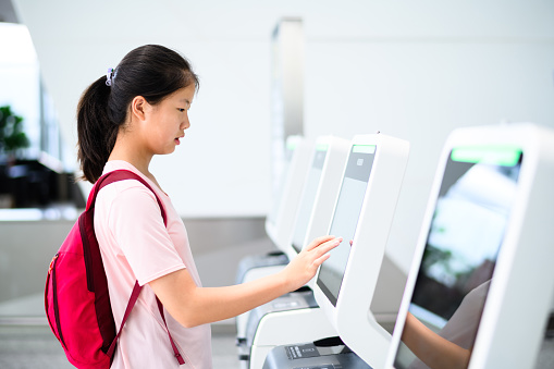 Asian teenage girl using self service at the airport