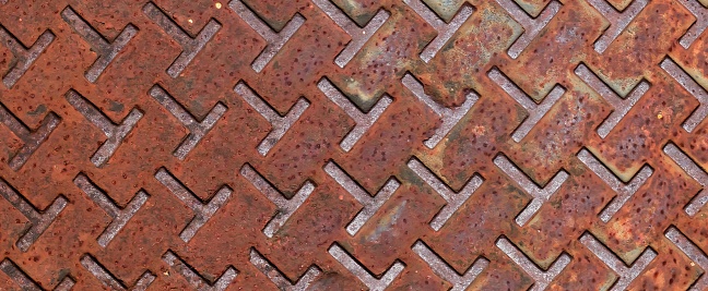 a photography of a metal grate with a pattern of squares, manhole cover with a pattern of squares and a diamond pattern.