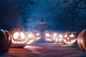 Halloween Backdrop. Halloween Pumpkins In Spooky Forest At Night. Gloomy forest sunset with haunted evil glowing eyes of Jack O' Lanterns on scary halloween night. 3d rendering