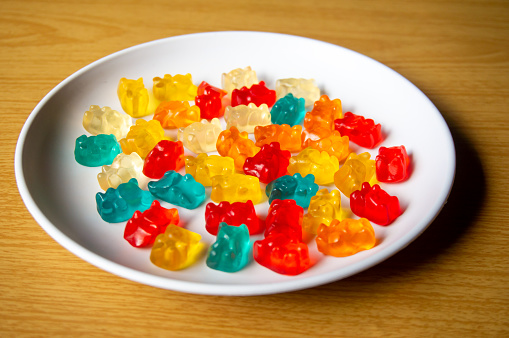 Sweet jelly bear candy on a white plate with a wood pattern background