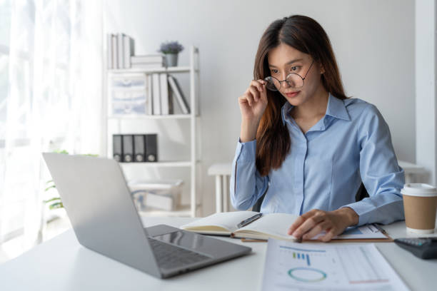 istock Confident asian businesswoman sitting and taking notes in notebook from laptop computer on financial, tax, income, expense, corporate issues for meeting preparation discuss in the office. 1635446567