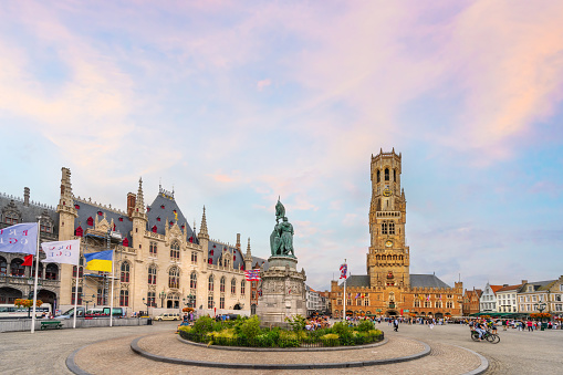 Bruges, Belgium - June 28, 2023: The historic town square Markt in the heart of Bruges city center. The city's most famous monuments is the 12th-century bell tower with restaurants, cafes and shops against the medieval buildings.