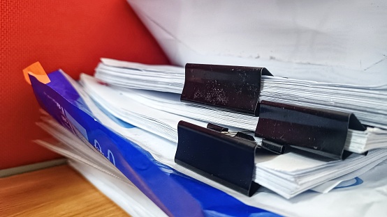 Jakarta, Indonesia - August 2023 : Stack of white papers separated by paperclips on office table.