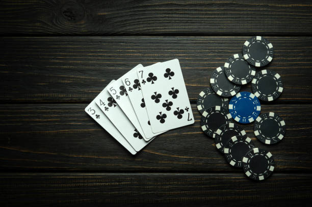 istock Popular poker game with straight flush winning combination. Cards with chips on a black vintage table in a poker club. Free black space for ads 1635473934