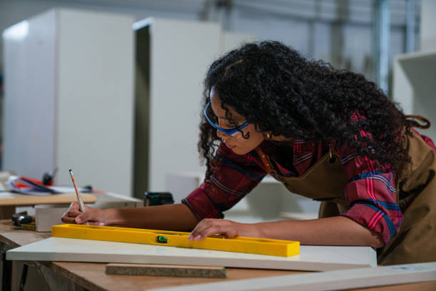istock Young woman working as carpenter in a small carpentry workshop. 1635492709