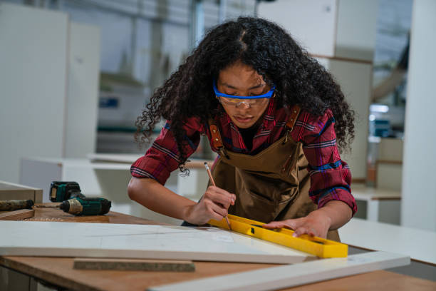 istock Young woman working as carpenter in a small carpentry workshop. 1635492712