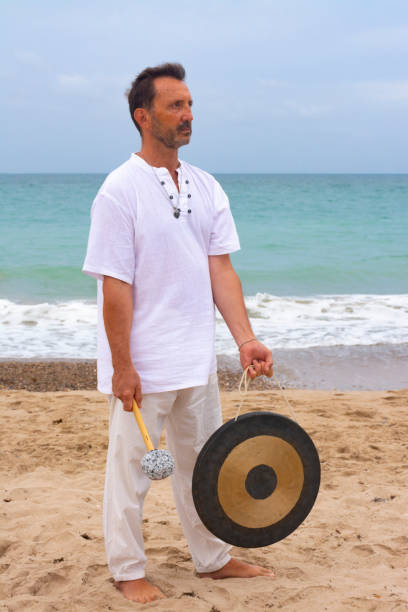 istock Man with a gong in the beach 1635499585