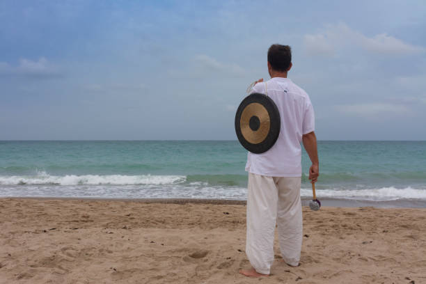 istock Man with a gong in the beach 1635503426