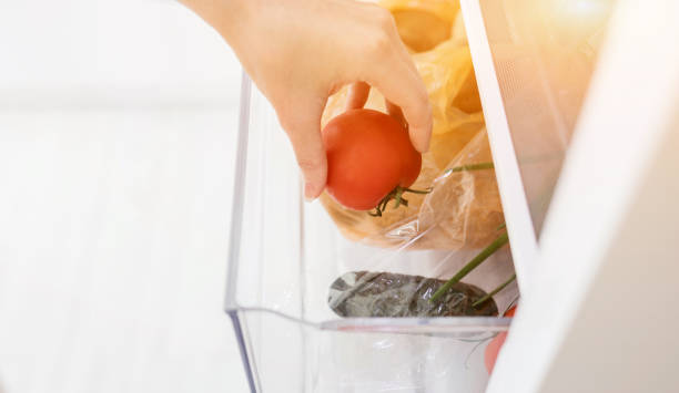 istock hand picks up tomato from the refrigerator 1635517894