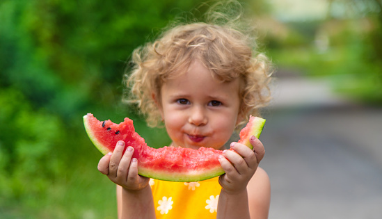 A child eats watermelon in the park. Selective focus. Kid.