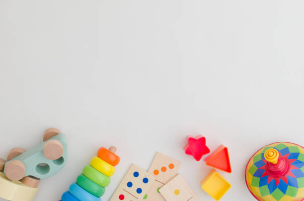 Top view of toddler toys Top view of scattered colorful toddler toys such as a spinning top, stacking rings and wooden cars with copy space on homogeneous background. lacher stock pictures, royalty-free photos & images