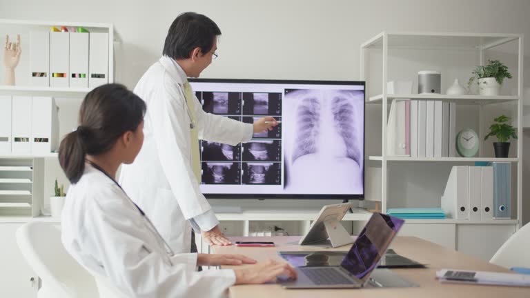 A medical and nurse cardiologist team meeting in the hospital and analyzed the patient's X-ray film on a TV screen.