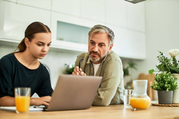 istock A senior man with his granddaughter using a laptop in the kitchen, both looking serious. 1635551270