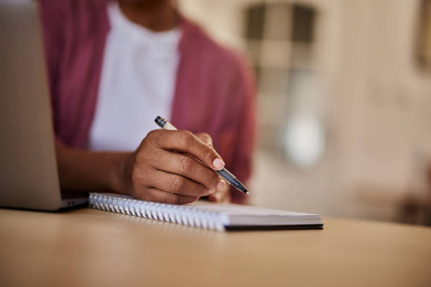istock A close-up of an unknown female writing notes in a notebook at the wooden table. 1635551505