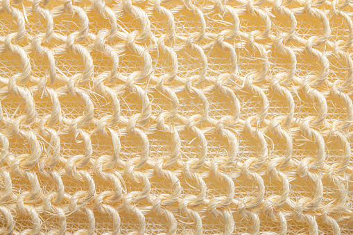 Close up view of braided string bath sponge texture. Beige pastel color texture.