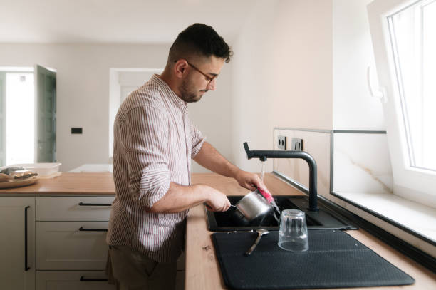 istock Young man washing dishes at home 1635559122