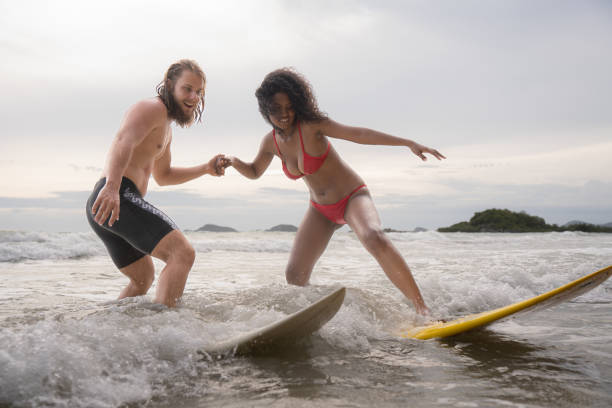 istock Couple surfing on the beach having fun and balancing on the surfboard 1635561273