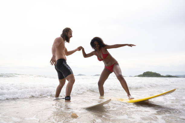 istock Couple surfing on the beach having fun and balancing on the surfboard 1635561292
