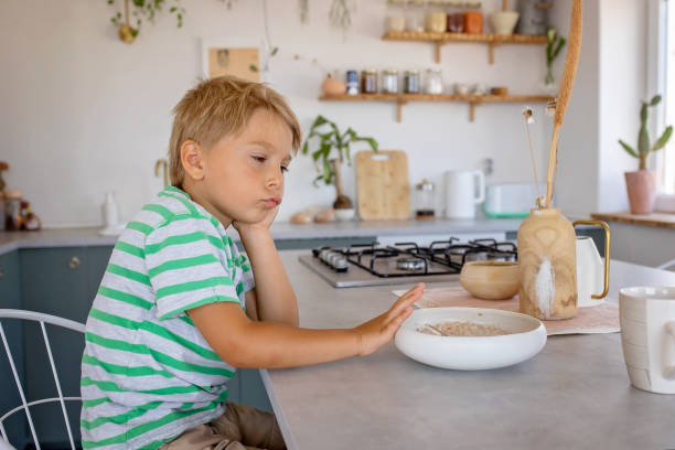 아름다운 금발의 아이, 소년, 아침에 집에서 아침 식사로 시리얼을 먹기를 거부 - eating cereal student human mouth 뉴스 사진 이미지