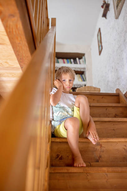 istock Cute blond child, boy, sitting on staircase, sad and lonely 1635575147