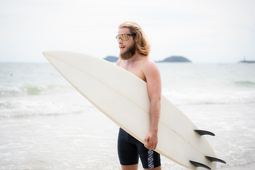 Surfer man with his surfboard on the beach.