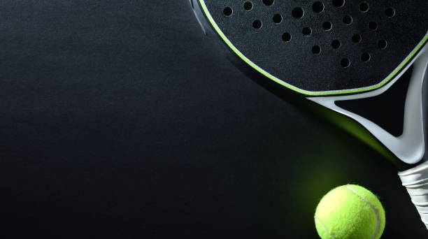 Background of black padel racket and ball on black background stock photo