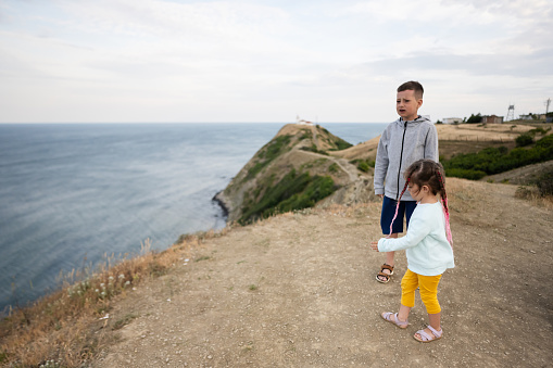 Cute little girl and her brother looking at the sea from the top of the mountain. Cape Emine, Black sea coast, Bulgaria.