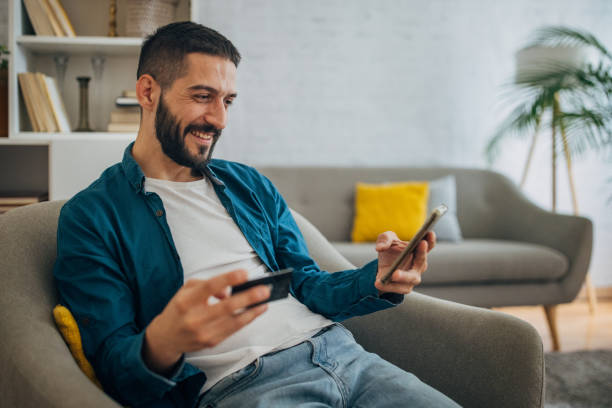 istock Man using mobile phone at home to shop online 1635606500