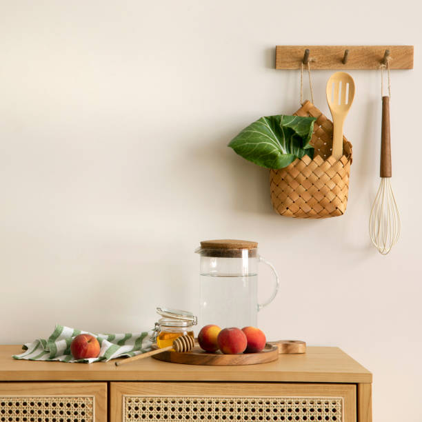 istock Interior design of of kitchen space with rattan commode, boho chair, ladder,  cutting board, herbs, vegetables, bread, eggs, pitcher, food and kitchen accessories. Home decor.  Template. 1635607041