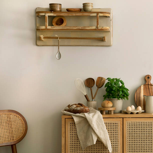 istock Interior design of kitchen space with rattan commode, boho chair, ladder,  cutting board, herbs, vegetables, bread, eggs, pitcher, food and kitchen accessories. Home decor.  Template. 1635607079