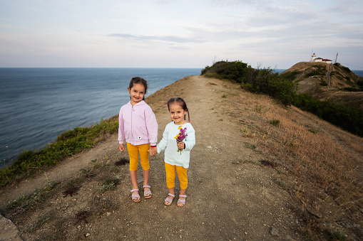 Two little girls walking on a mountain path against sea. Cape Emine, Black sea coast, Bulgaria.
