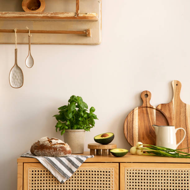 istock Creative composition of kitchen space with rattan commode, hanging cupboard, herbs, vegetables, avocado, wooden cutting boards, pitcher, food and kitchen accessories. Home decor. Template. 1635608738