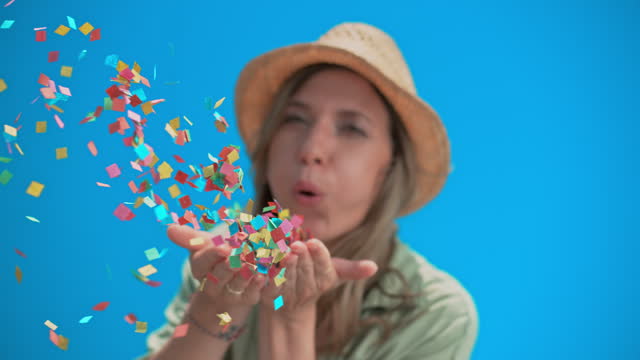 SLO MO Indian woman blowing confetti off her palms against the blue sky