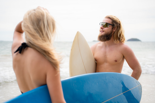Young man and woman holding surfboards ready to walk into the sea to surf.