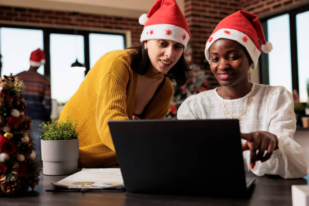 istock Coworkers in santa hats checking report 1635627876
