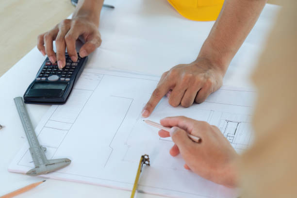 istock Architect man holding pencil working with blueprints for architectural plan 1635627883