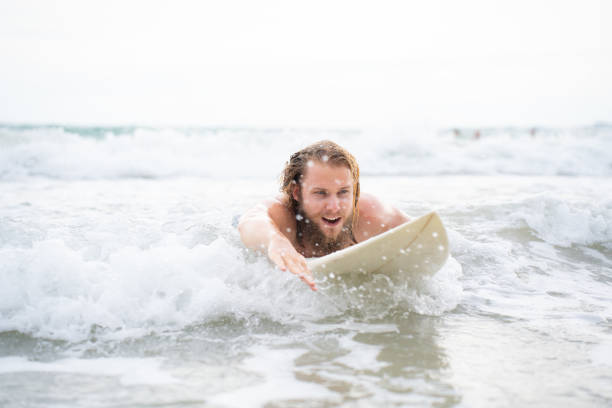 istock Young man surfing on the beach having fun and balancing on the surfboard 1635630581