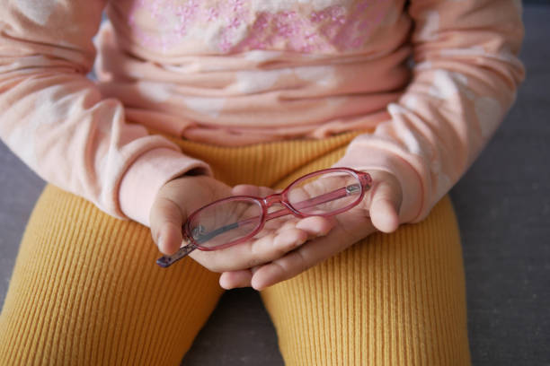 child holding a eyeglass sitting on sofa ,