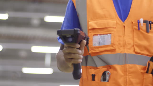 Warehouse employee using handheld barcode reader, doing inventory management