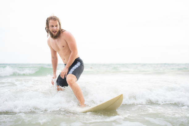 Asian play surf alone on the summer beach. Solo outdoor activity on holiday